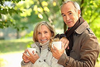 Middle-aged couple drinking coffee in park
