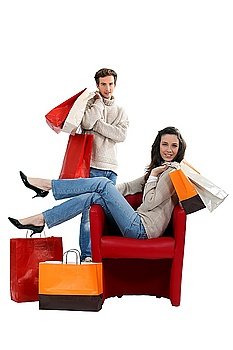 Woman sitting in a chair and surrounded by shopping bags