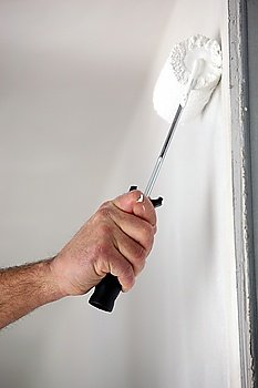 Close-up of man painting wall with roller