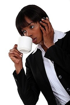 Afro-American businesswoman talking on her cell and drinking coffee