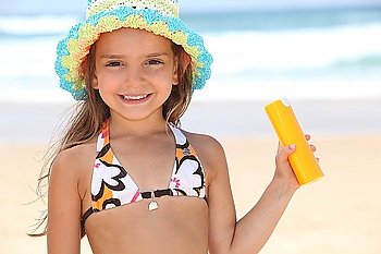 Young girl on the beach holding suncream