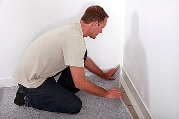Man installing carpet in room