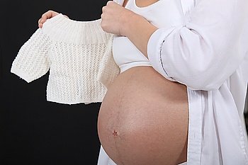 Pregnant woman holding a baby´s jumper