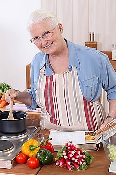 Elderly woman cooking with the help of a recipe