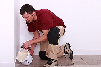 Man pouring tile adhesive over an old floor