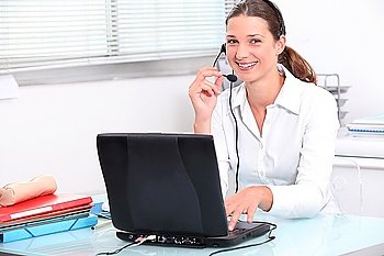 Young woman using a laptop computer and telephone headset