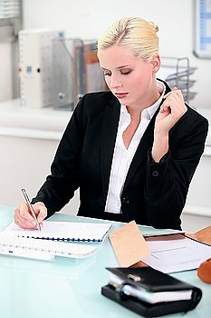 Young businesswoman writing notes at her desk