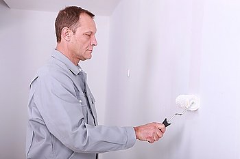 Decorator painting a room white with a roller