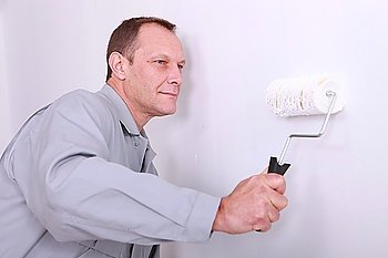 Decorator painting a wall white