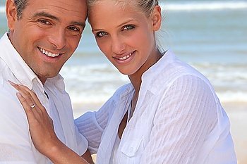 Couple wearing white clothing stood on a beach