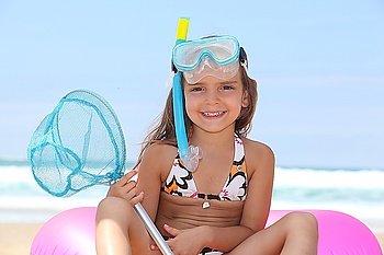 Young girl on the beach with snorkel, mask and fishing net