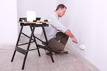 Man with paint roller kneeling