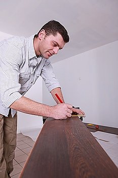 Man marking parquet floor before cutting to size