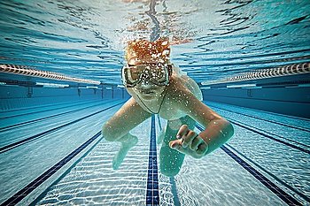 Boy swimming under water in pool