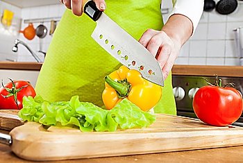 Woman´s hands cutting fresh bell pepper on kitchen