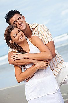 A young man and woman having fun dancing as a romantic couple on a beach with a bright blue sky