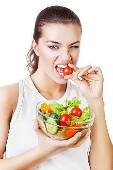 agressive woman biting tomato on white background