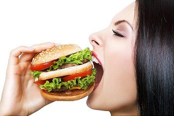 girl biting hamburger with widely opened mouth on white background