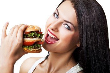 happy cute woman eating hamburger on white background