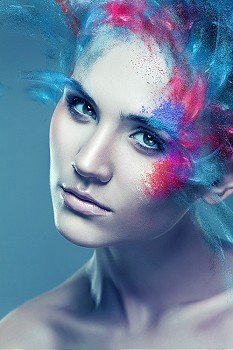 woman with flying coloured powder above eye