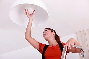 young woman on ladder changing bulb