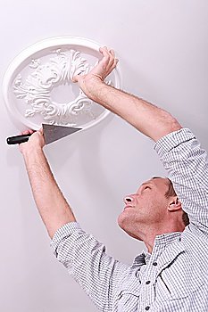 Decorator affixing a ceiling rose
