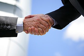 Two businesspeople shaking hands outdoors