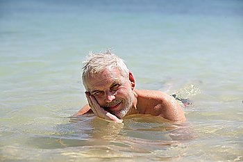 Grey-haired man laying in the sea