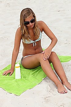 Young woman applying sunblock at the beach