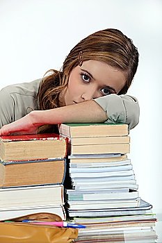 Young woman laying her head on a stack of books