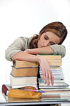student sleeping over a pile of books