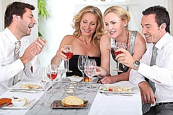 Four joyful people at the start of a posh dinner.