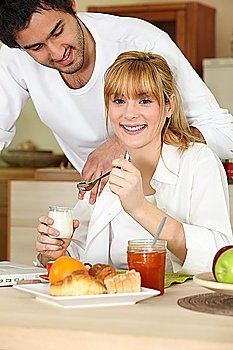 Woman eating breakfast while her affectionate boyfriend gazes at her