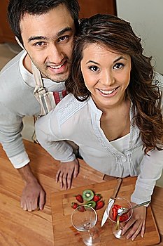 high angle shot of couple all smiles slicing fruits