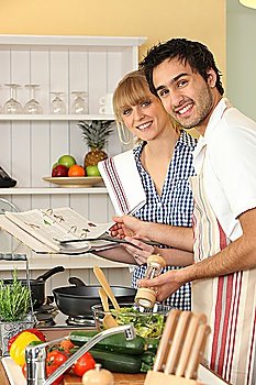 Couple preparing a meal with the help of a cookbook