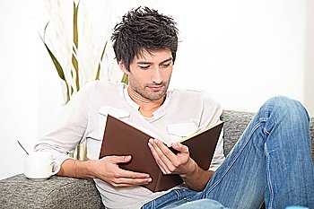 Man reading a book on a sofa