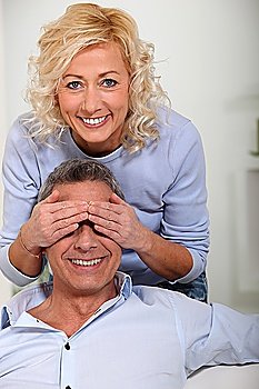 Woman covering her husband´s eyes with her hands