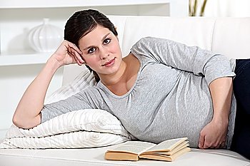 Pregnant woman reading in bed