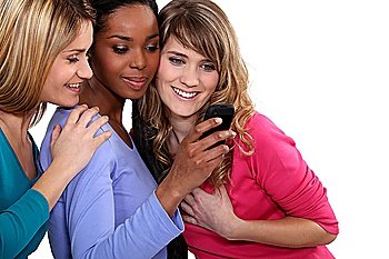 Three female friends looking at mobile telephone