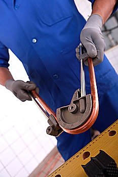 Worker using a tool to bend a copper tube