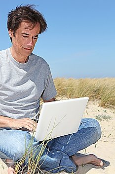 Man on laptop at the seaside