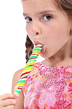 little girl licking a lollipop