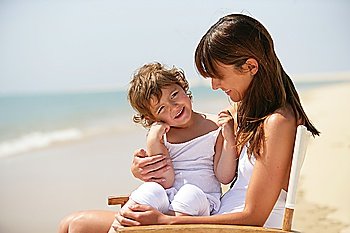Mother and daughter sat on chair at the beach
