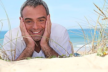 Happy man lying on the sand