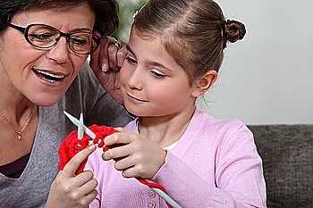 A mother teaching her daughter how to knit.