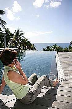 Senior woman making a call by the pool