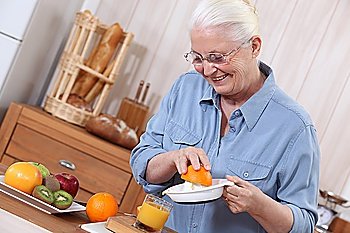 Elderly lady squeezing orange juice