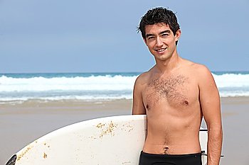 Young man at the beach with surfboard