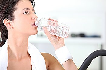 Woman drinking a bottle of water at the gym
