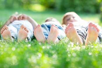 Group of happy children lying on green grass in spring park